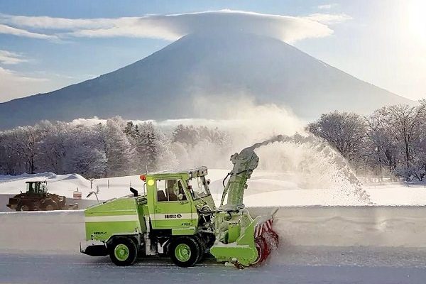 snow plough clearing huge quantities of Japan snow in front of Mount Youtei at Japan skiing resort