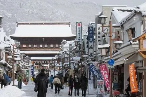 people walking down snowy street towards zenkoji temple in nagano city