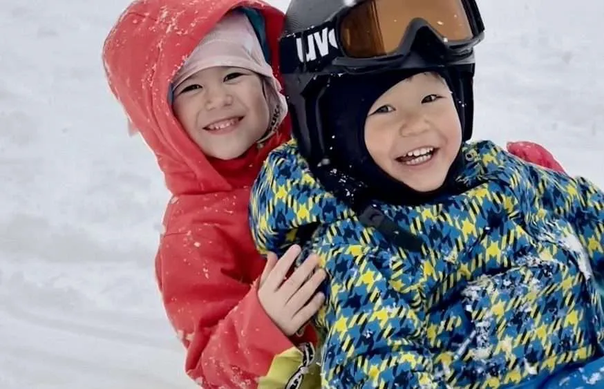 children sledging in the snow enjoying their japan ski vacation