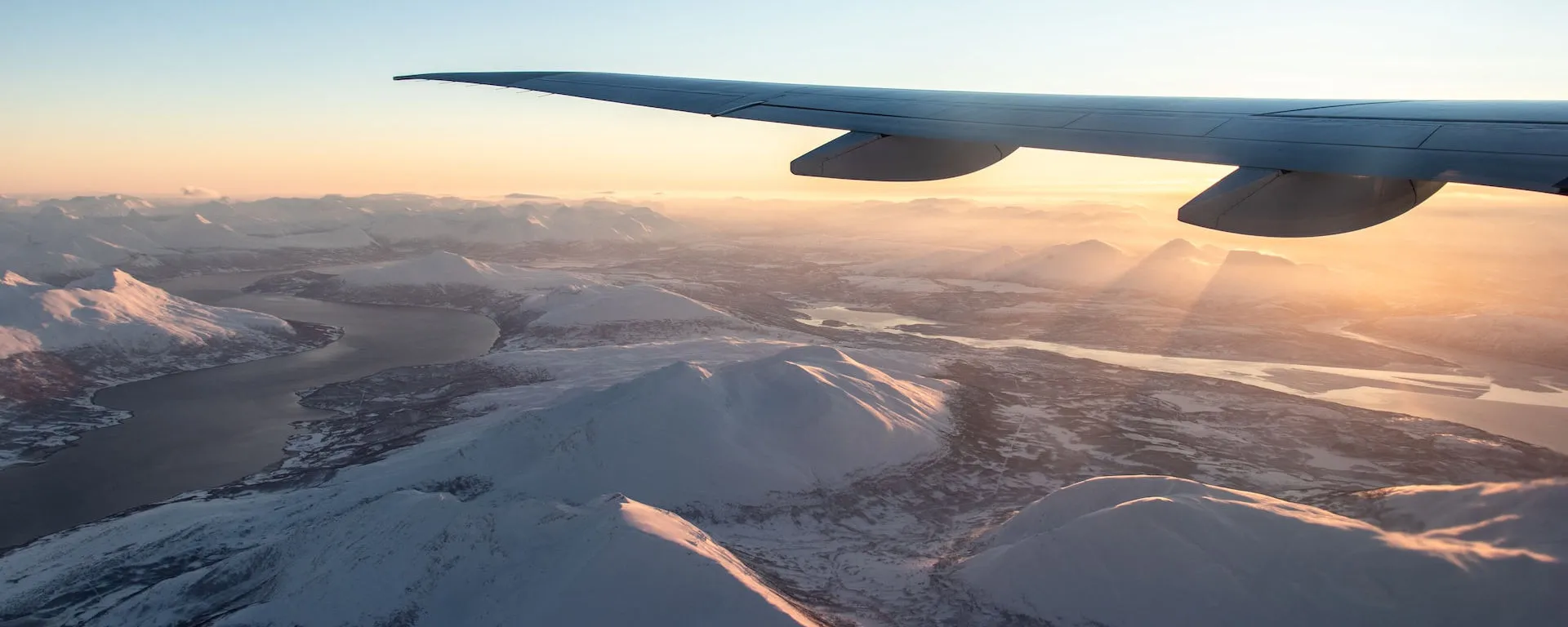 Passenger airplane flying over snow-covered mountains.