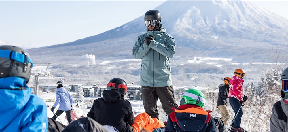 A group of people taking a ski lesson with Mount Yotei in the background.