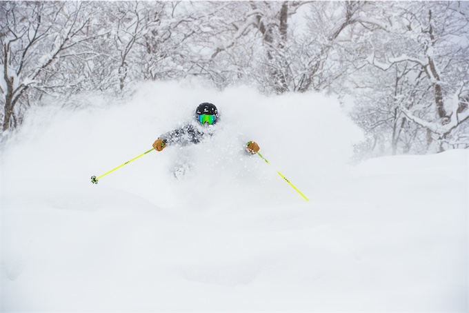 Skier buried in deep white powder snow while skiing through a winter forest.