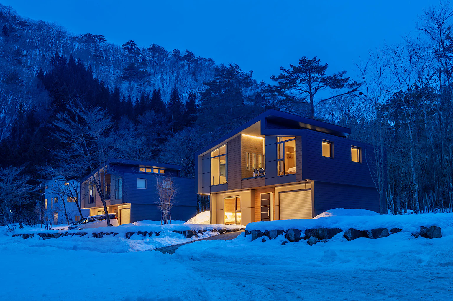 Modern apartment lodge with glowing windows in a snowy forest.