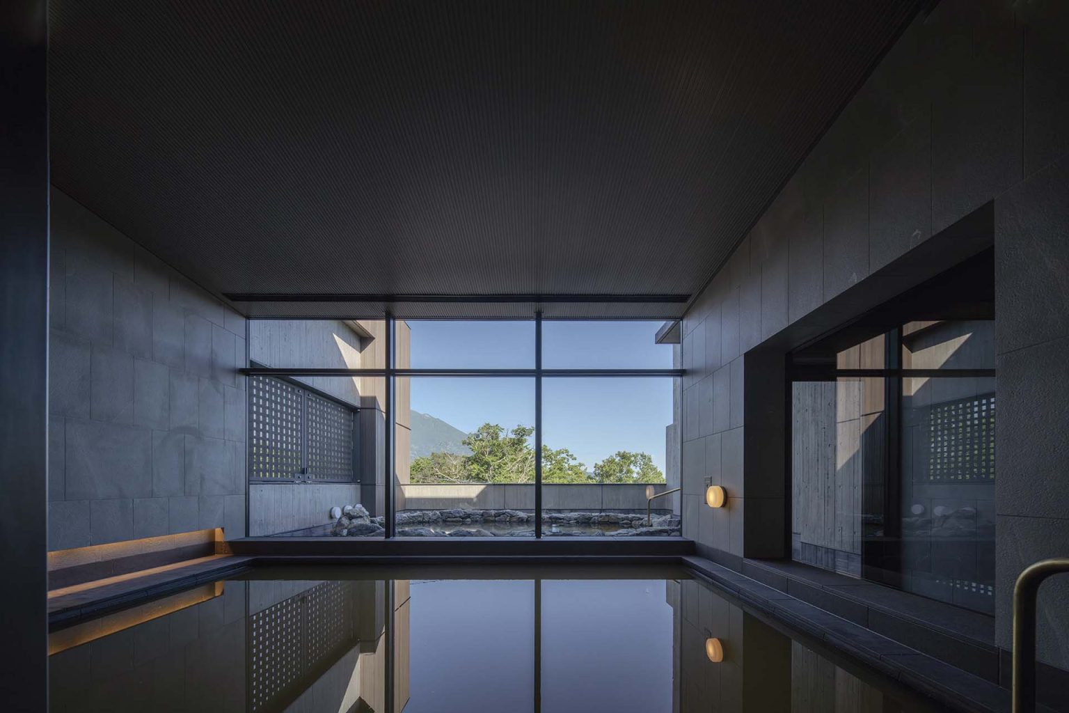 Onsen in Niseko featuring indoor bath an a large window with views of trees and the sky