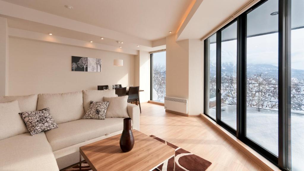Modern living room with a beige sectional, wooden coffee table, and large windows overlooking a snowy landscape.
