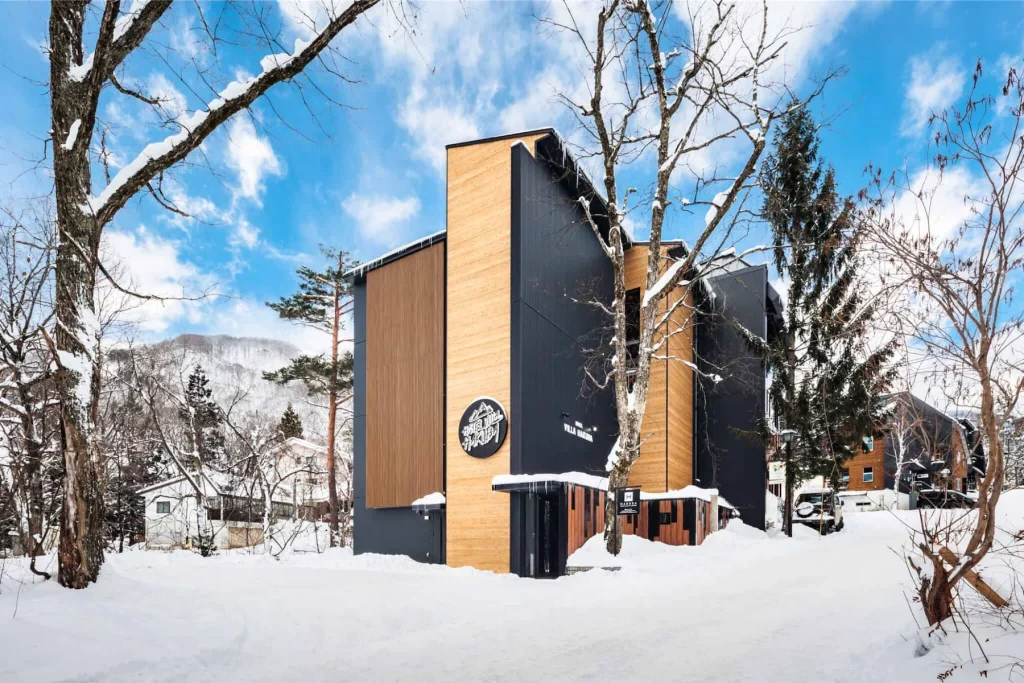 Hotel Villa Hakuba building featuring modern black and wood siding in winter snow.