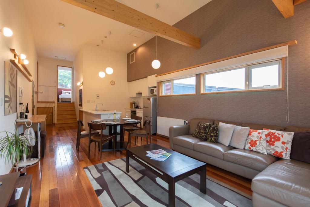 Modern living room with leather sofa, vaulted ceiling, and wooden floors in a contemporary home.