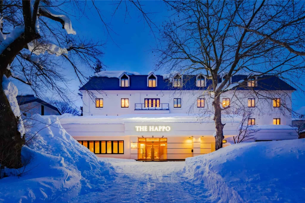 The Happo hotel entrance glowing at twilight with deep snow banks on the driveway.