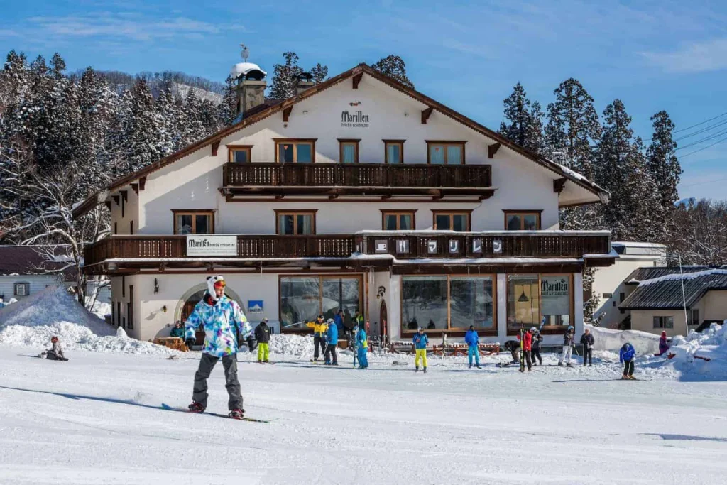 Ski-in ski-out alpine chalet of Marillen Hotel with skiers on the snowy slopes.