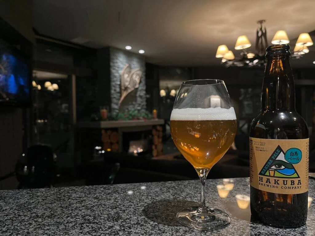 A glass of Hakuba Pale Ale beer on a bar counter next to the bottle in a bar lounge.
