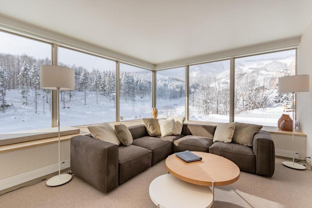 Luxury lounge with a large sectional sofa and panoramic windows overlooking a snowy forest.