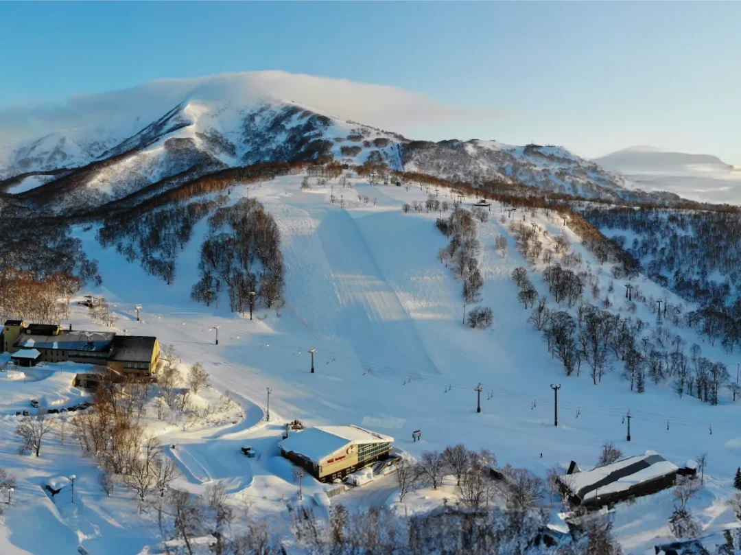 Panoramic winter view of Niseko Annupuri ski resort slopes and buildings at sunset in Annupuri, Japan.