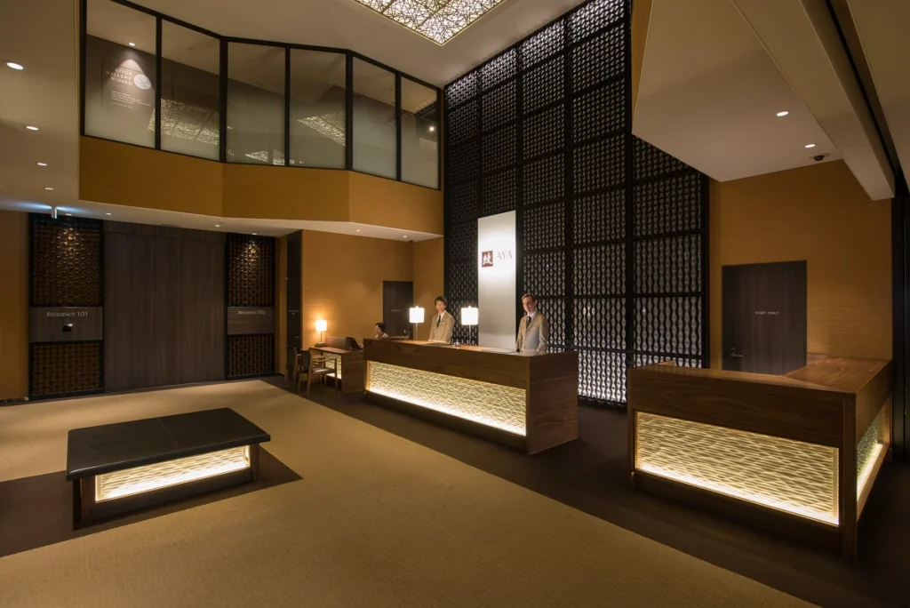 Modern luxury hotel lobby with wooden reception desks and warm accent lighting.
